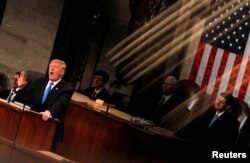 FILE - U.S. President Donald Trump is seen under the reflection of a House chamber railing as he delivers his State of the Union address to a joint session of the U.S. Congress on Capitol Hill in Washington, Jan. 30, 2018.