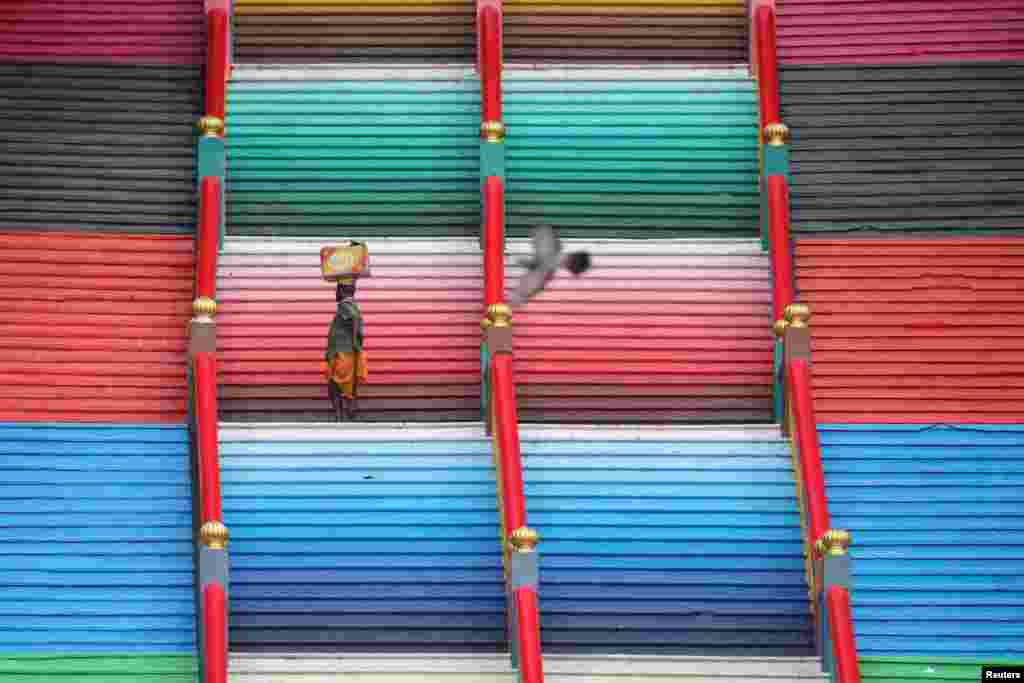 A man carries a box while climbing steps to Batu Caves in Kuala Lumpur, Malaysia.