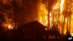 A wildfire burns behind a home on Twisp River Road, Aug. 20, 2015 in Twisp, Wash.