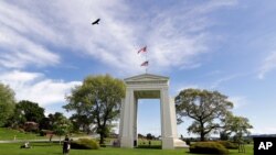 In this May 17, 2020, photo, a bird flies from the U.S. into Canada over the Peace Arch in Peace Arch Historical State Park on the border with Canada, where people can walk freely between the two countries at an otherwise closed border in Blaine, Wash..