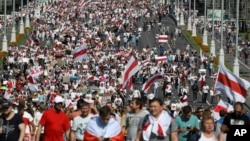 Belarusian opposition supporters with old Belarusian national flags rally in Minsk, Belarus, Sunday, Aug. 30, 2020. Tens of thousands of demonstrators gathered in the capital of Belarus, beginning the fourth week of daily protests demanding that the…