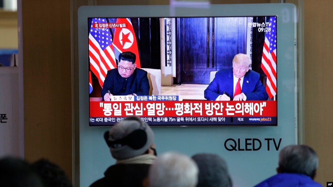 Sebuah acara TV memperlihatkan foto Presiden AS, Donald Trump, dan pemimpin Korut, Kim Jong Un, kiri, dan di saat yang sama tampak pemirsa menyimak pidato Tahun Baru Kim, di Stasiun Kereta Api Seoul, Korea Selatan, 1 Januari 2019 (foto: AP Photo/Ahn Young-joon)
