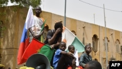 FILE —Young boys gather on top of a car while displaying flags of Niger, Burkina Faso and Russia during a demonstration for the immediate departure of United States Army soldiers deployed in northern Niger in Niamey, on April 13, 2024.