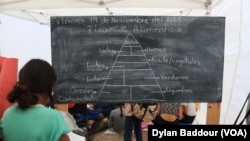 A girl copies the food pyramid at the Sidewalk School for Children Asylum seekers in Reynosa. (Dylan Baddour/VOA)
