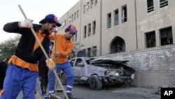 Workers sweep away debris after a bombing in Baghdad, Iraq, 23 Jan 2011.