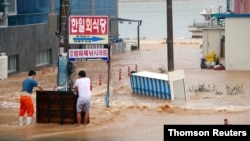 Men stand on a street submerged by typhoon Haishen in Gyeongju