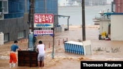 Men stand on a street submerged by typhoon Haishen in Gyeongju, Sep. 7, 2020.