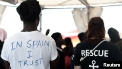 A migrant wearing a t-shirt reading "In Spain I Trust" waits to disembark from the Aquarius rescue ship at port in Valencia, Spain, June 17, 2018, after Italy refused to accept the migrants on board.