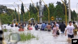 FILE - People walk in the water as they leave the flooded area of Santa Fe, some 390 kilometers, (250 miles) northwest of Buenos Aires, Argentina, April 30, 2003.