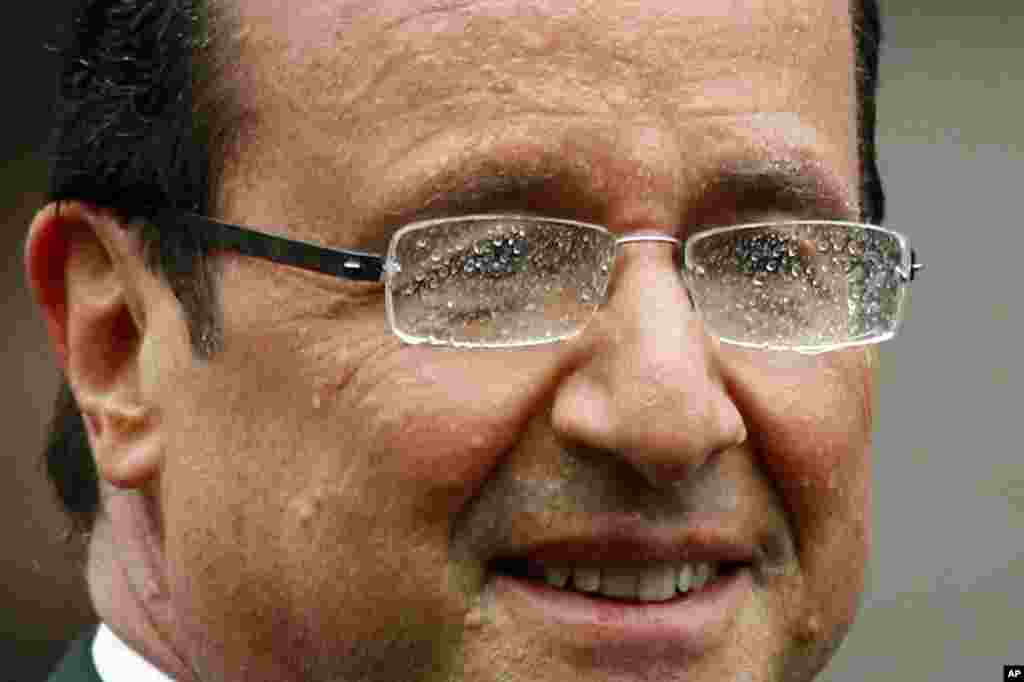 Hollande smiles from his car during a rain shower on the Champs Elysees. 