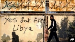 A Libyan man walks past graffiti on a wall reading "Yes for Free Libya" in Benghazi, Libya, April 13, 2011