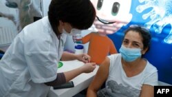 A healthcare worker administers a COVID-19 vaccine to an Israeli woman at Clalit Health Services, in the coastal city of Tel Aviv, Jan. 3, 2021.