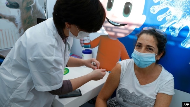 A healthcare worker administers a COVID-19 vaccine to an Israeli woman at Clalit Health Services, in the coastal city of Tel Aviv, Jan. 3, 2021.