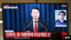 Um homem assiste ao discurso do Presidente da Coreia do Sul, Yoon Suk Yeol, durante um noticiário transmitido por uma televisão numa estação de comboios em Seul, a 3 de dezembro de 2024.