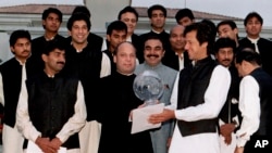 کرکٹ ورلڈ کپ 1992ء کی فاتح پاکستانی ٹیم کے کپتان عمران خان اس وقت کے وزیرِ اعظم میاں نواز شریف کی جانب سے دیے جانے والے عشائیے کے موقع پر انہیں ورلڈ کپ دے رہے ہیں۔ (فائل فوٹو)