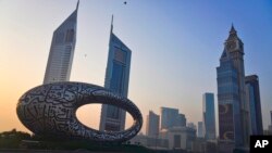 Pengendara sepeda berkendara di jalan raya utama dengan Museum of the Future dan Emirates Towers di belakang mereka di Dubai, Uni Emirat Arab. (Foto: AP)