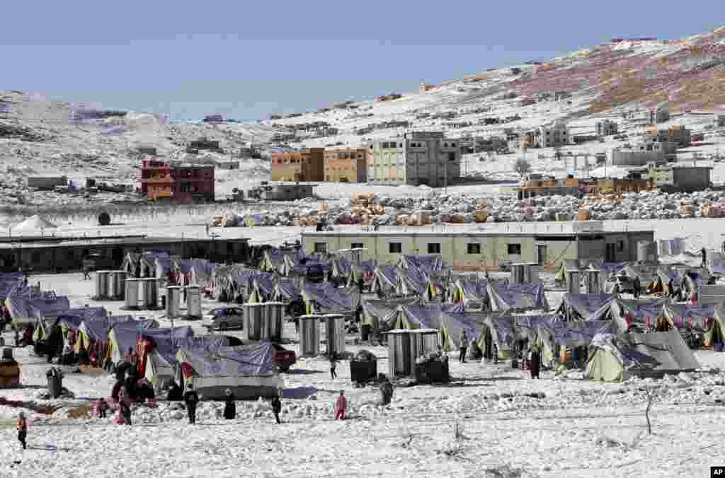 Syrian refugees walk outside their tents at a camp in the eastern Lebanese border town of Arsal, Dec. 15, 2013. 