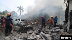 Bomberos tratan de extinguir el incendio que rodea los restos del avión militar indonesio que se estrelló en Medan, Indonesia, el martes, 30 de junio de 2015.