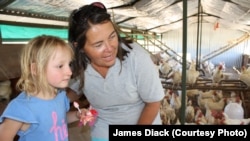 Farmer Ruth Mylroie witnesses a chicken laying an egg with a young visitor during a school tour of New Harmony Farm