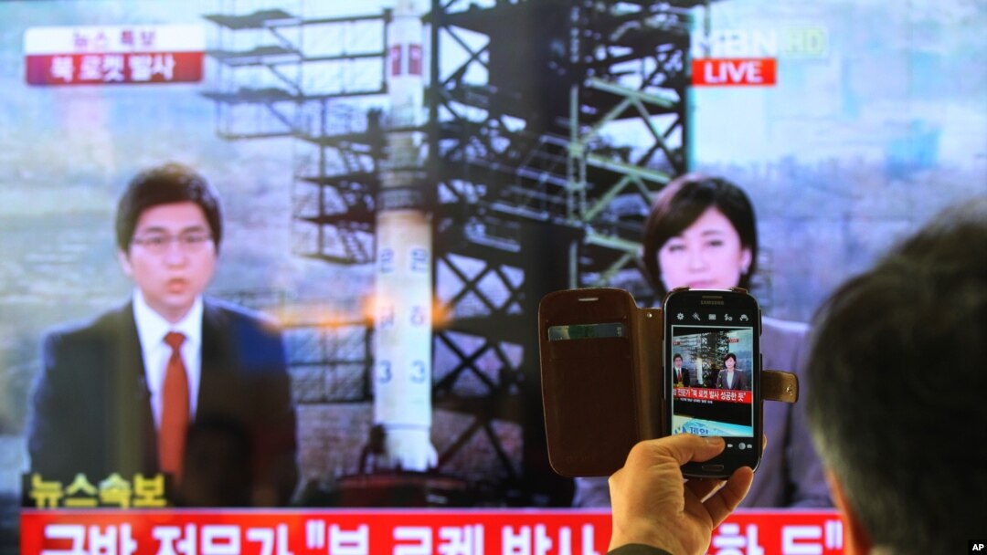 Seorang warga Korsel menggunakan telepon pintarnya untuk memotret siaran televisi yang memberitakan peluncuran roket Korea Utara di Stasiun Kereta Api di Seoul, Korsel (12/12). 
