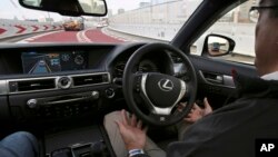 FILE - An employee of Toyota Motor Corp., drives automated driving test vehicle during a test drive of Toyota's self-driving technologies in Tokyo. Such cars are one field in which researchers are seeking to expand the limits of machine learning.