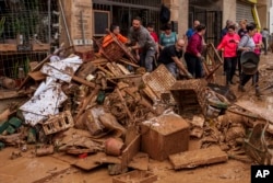 People clean mud from a shop affected by floods in Chiva, Spain, Nov. 1, 2024.