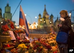 FILE - A woman lays a bunch of flowers at a place where Boris Nemtsov was gunned down on Feb. 27, 2015.