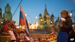 FILE - A woman lays a bunch of flowers at a place where Boris Nemtsov was gunned down on Feb. 27, 2015.