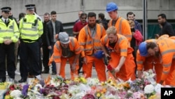 City workers lay flower tributes in the London Bridge area of London, Monday, June 5, 2017.