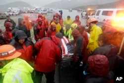 Emergency personnel huddle around the body of a volunteer member of the Ventura County search and rescue team, killed in a traffic accident along Interstate Highway 5 south of Pyramid Lake, Calif., Feb. 2, 2019.