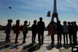 Tourists pose for a souvenir photo on Trocadero with the Eiffel Tower in background on a sunny day in Paris, Thursday, March 30, 2017. France is experiencing heat wave condition with temperatures crossing 22 degrees Celsius (72 Fahrenheit) in several areas.