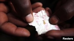 FILE - A Congolese mineral trader holds a piece of paper containing nuggets of gold in a mud hut at Numbi in eastern Congo.