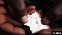 FILE - A Congolese mineral trader holds a piece of paper containing nuggets of gold in a mud hut at Numbi in eastern Congo.