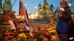 FILE - A woman lays a bunch of flowers where Boris Nemtsov was gunned down on Feb. 27, 2015.