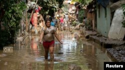 Seorang perempua berjalan mengarungi genangan air menyusul Taifun Vamco, di San Mateo, Provinsi Rizal, Filipina, Jumat, 13 November 2020. 