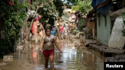 A woman wades through muddy floodwater following Typhoon Vamco, in San Mateo, Rizal province, Philippines, Nov. 13, 2020. 