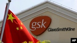 FILE - A Chinese flag is hoisted in front of a GlaxoSmithKline building in Shanghai, China. Police accused Peter Humphrey, a British executive of drug maker GlaxoSmithKline, on May 14, 2014, of leading a sprawling scheme to bribe doctors and hospitals to 