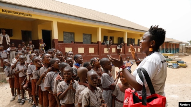 Jumoke Olowookere speaks to children at a school as she prepares them to repaint a playground made from used tires in Ibadan Nigeria on February 22, 2022. (REUTERS/Temilade Adelaja)