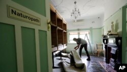 Aaron Brocken membersihkan klinik naturopati ibunya di Windsor, barat laut Sydney, New South Wales, yang terdampak banjir, Kamis, 25 Maret 2021. (AP Photo/Rick Rycroft)