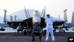 American navy officers talk to each other aboard the aircraft carrier USS Carl Vinson as it docks in Danang bay, Vietnam on Monday, March 5, 2018. (AP Photo/ Hau Dinh)