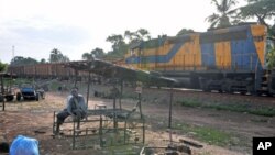 Residents sit near a train pulling carriages with bauxite in Kamsar, Guinea, October 2008. (file photo)