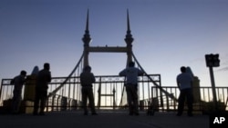 Cambodian police officers stand guard on a bridge where hundreds of people stampeded during a water festival in Phnom Penh, Cambodia, 28 Nov 2010