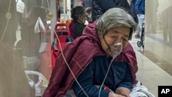 ARCHIVO – Una paciente de la tercera edad recibe una inyección por goteo intravenoso mientras usa un respirador en el corredor de una sala de emergencia en Beijing, el 5 de enero de 2023.
