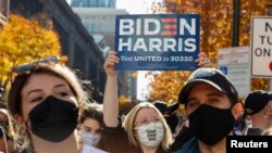 Seorang perempuan memegang poster Biden-Harris setelah media memproyeksikan Biden sebagai presiden terpilih di Philadelphia, Pennsylvania, 7 November 2020.