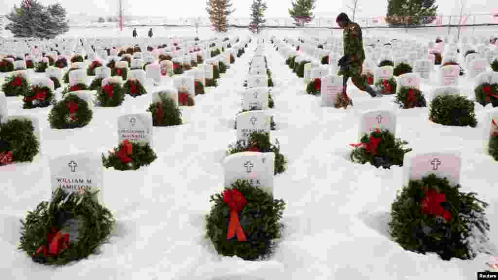 A volunteer walks through military graves at the Ft. Logan National Cemetery after Christmas wreaths were placed there in the Wreaths Across America event in Denver, Colorado, Dec. 17, 2016.