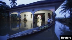 Seorang warga mengikat perahunya di depan rumahnya yang tergenang banjir di Tumpat, 500 kilometer sebelah timur laut Kuala Lumpur (26/12). 