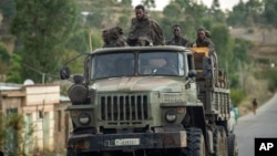 FILE - Ethiopian government soldiers ride in the back of a truck on a road leading to Abi Adi, in the Tigray region of northern Ethiopia, May 11, 2021.