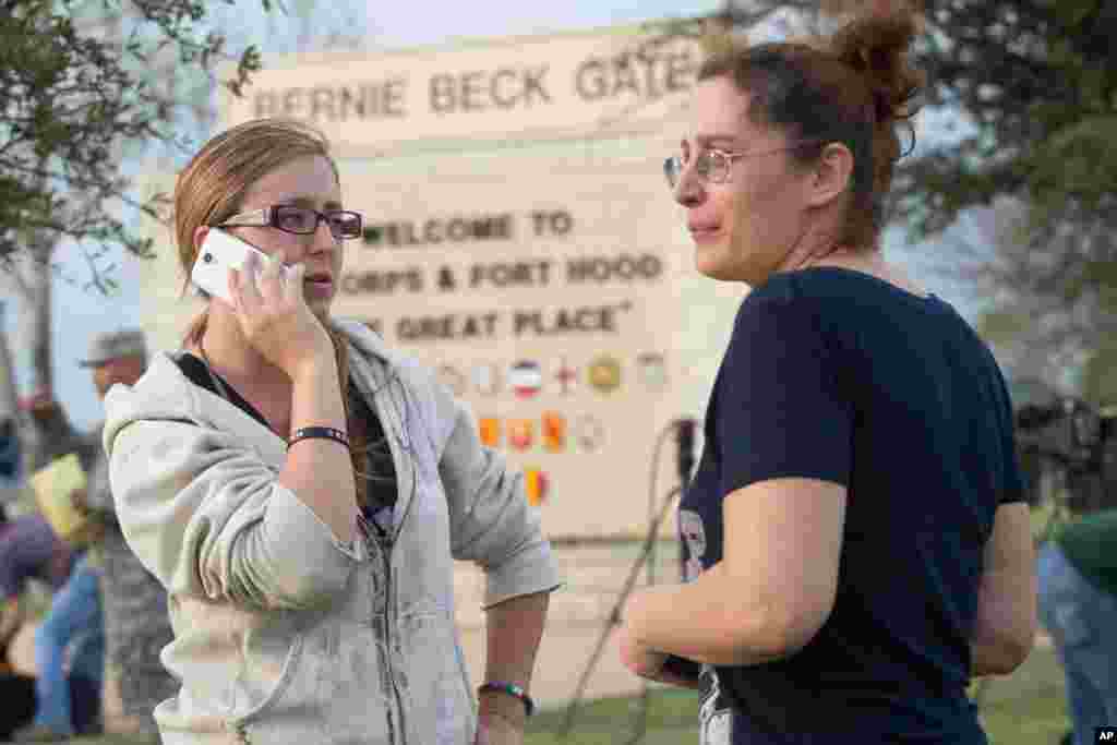 Krystina Cassidy dan Dianna Simpson mencoba menghubungi suami mereka yang bekerja di dalam Fort Hood, sambil berdiri di luar Bernie Beck Gate, 2 April 2014.
