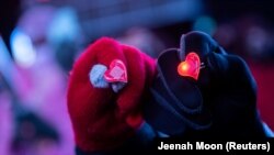 Sepasang kekasih menunjukkan cincin berbentuk hati pada hari Valentine di Manhattan, New York, Minggu, 14 Februari 2021. (Foto: Reuters)