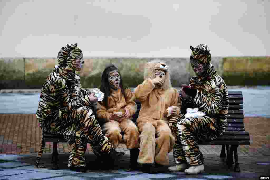 Two mothers and their children eat before participating in the parade of the Carnival in Gijon, northern Spain, Feb. 16, 2015.